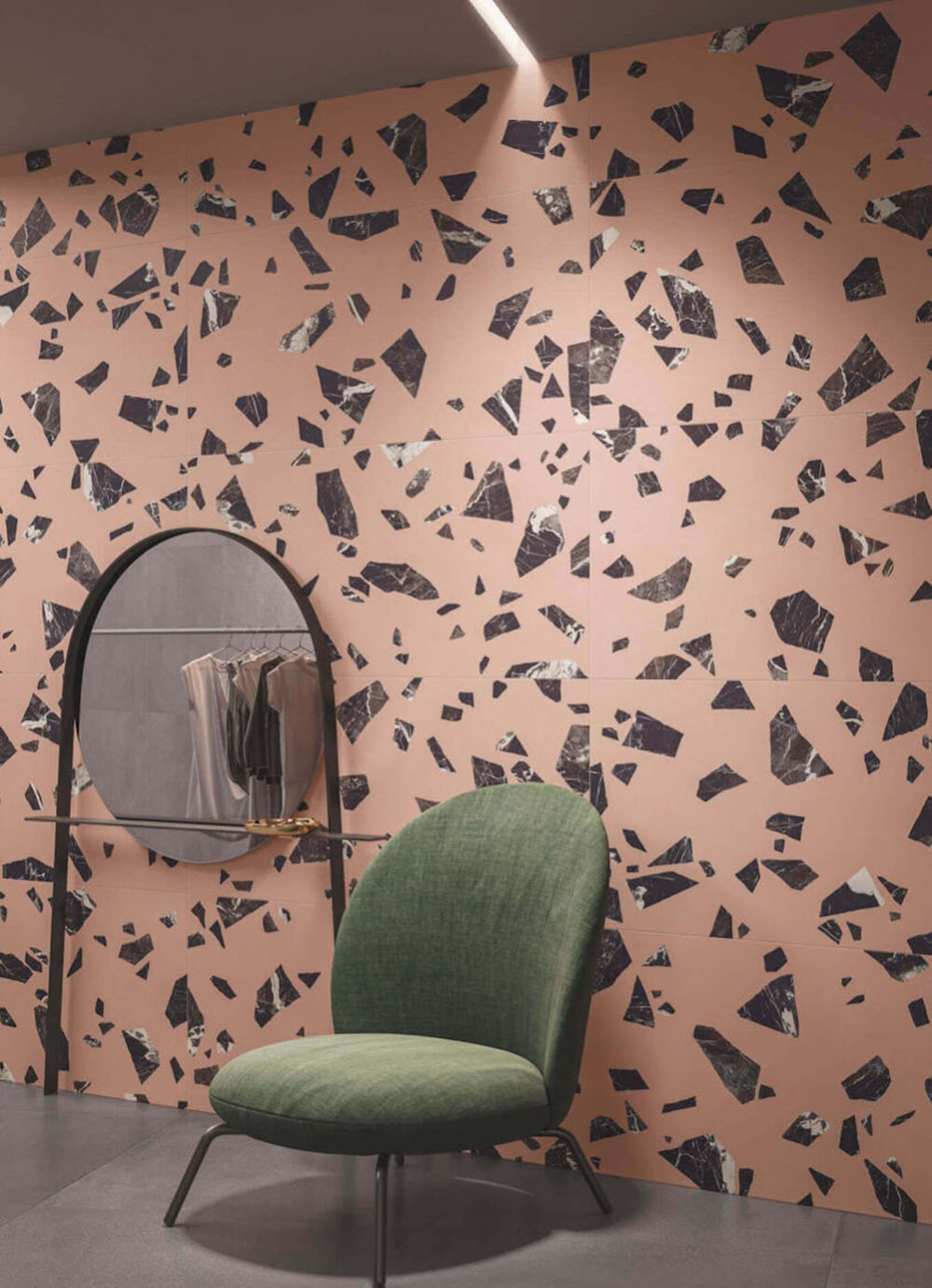 Contemporary interior featuring Melody ROCK Terrazzo Pink 60 × 60cm porcelain wall tiles, designed with oversized black marble-effect fragments set against a soft pink background, creating a bold terrazzo-inspired statement paired with modern furniture and deep charcoal flooring.