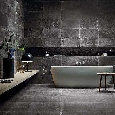 Lifestyle image of Monzo Stone Nite 30x60cm dark stone-effect porcelain wall and floor tiles, featuring rich charcoal tones, subtle veining and varied natural stone-inspired texture, styled within a contemporary bathroom with matte black accents and minimalist décor.