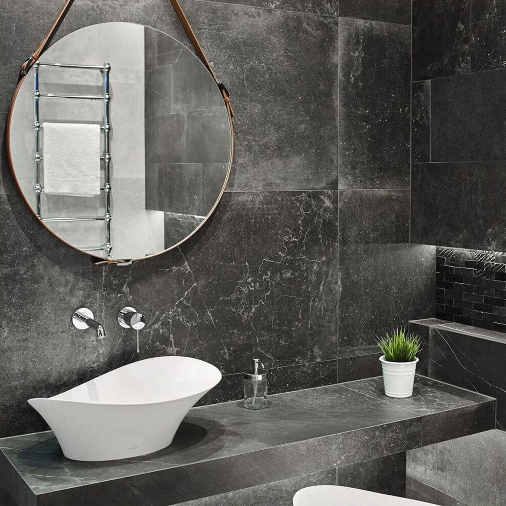 Lifestyle image of Monzo Stone Nite 60x60cm dark stone-effect porcelain wall and floor tiles in rich charcoal tones, featuring subtle veining and natural stone-inspired texture, styled within a modern bathroom with sleek black accents and contemporary fittings.