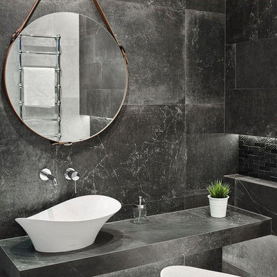 Lifestyle image of Monzo Stone Nite 60x60cm dark stone-effect porcelain wall and floor tiles in rich charcoal tones, featuring subtle veining and natural stone-inspired texture, styled within a modern bathroom with sleek black accents and contemporary fittings.