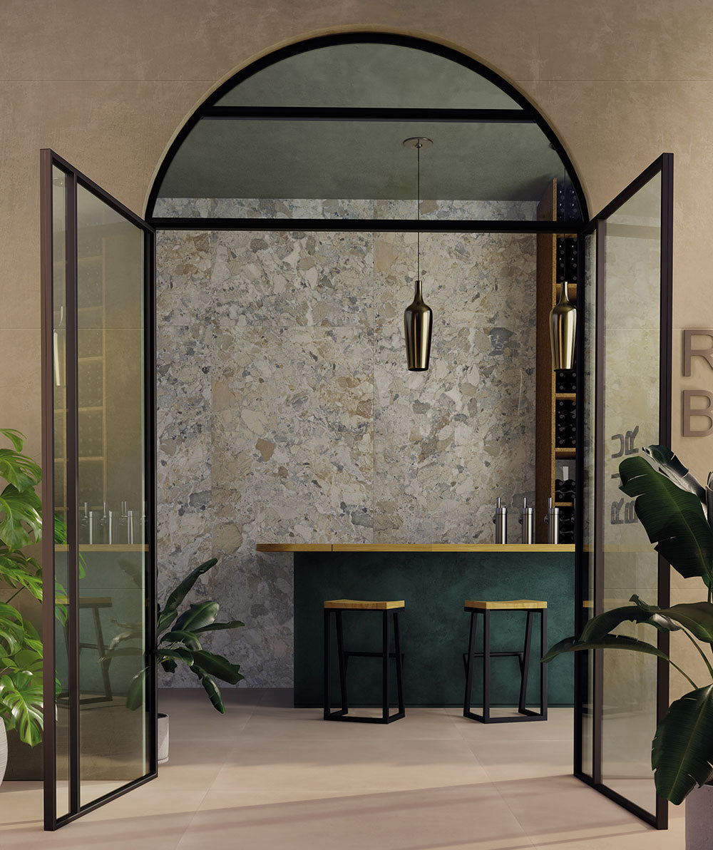 Interior featuring Museo Warm Stone Matt 60x120cm porcelain tiles, showcasing a striking marble effect design in warm beige, ivory and grey tones, paired with black-framed glazing, contemporary furnishings and botanical accents.