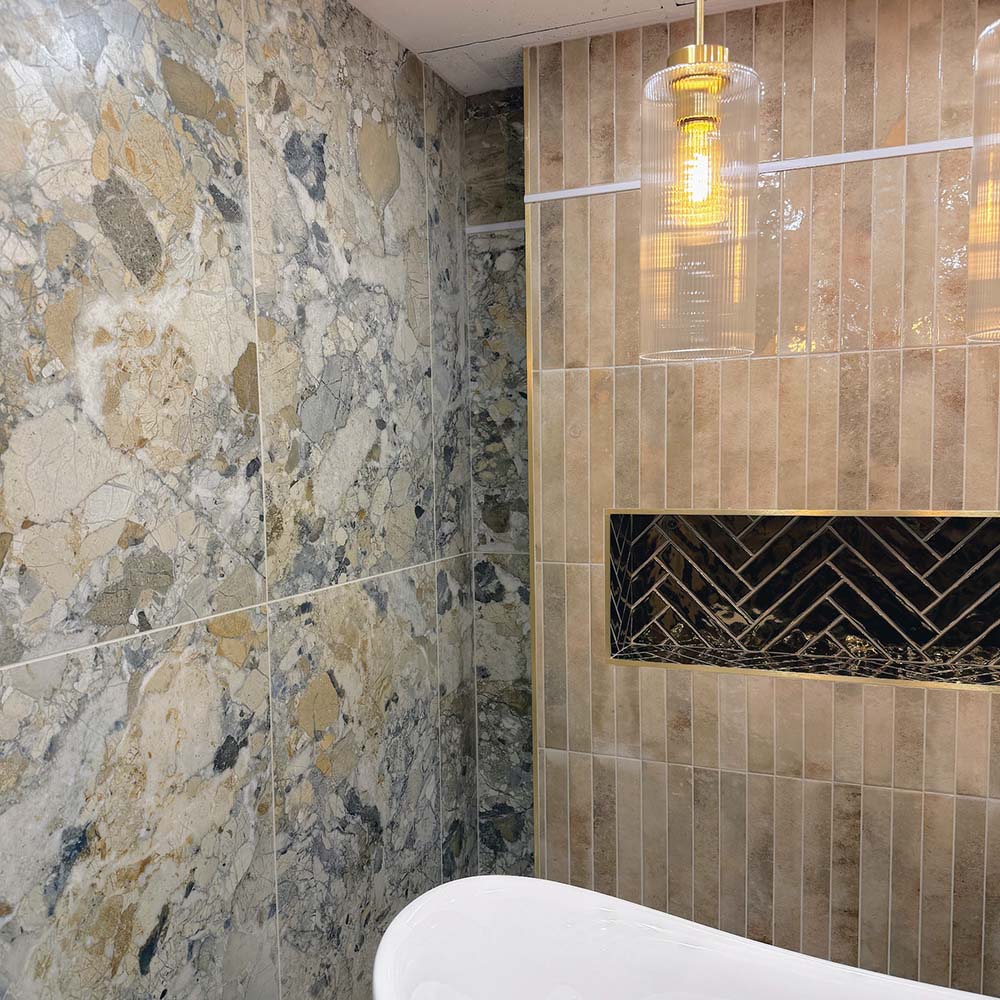 Bathroom featuring Museo Warm Stone Matt 60x120cm porcelain wall tiles, showcasing a bold marble effect design in warm beige, ivory and grey tones, complemented by textured neutral wall tiles, brass accents and a contemporary freestanding bath.