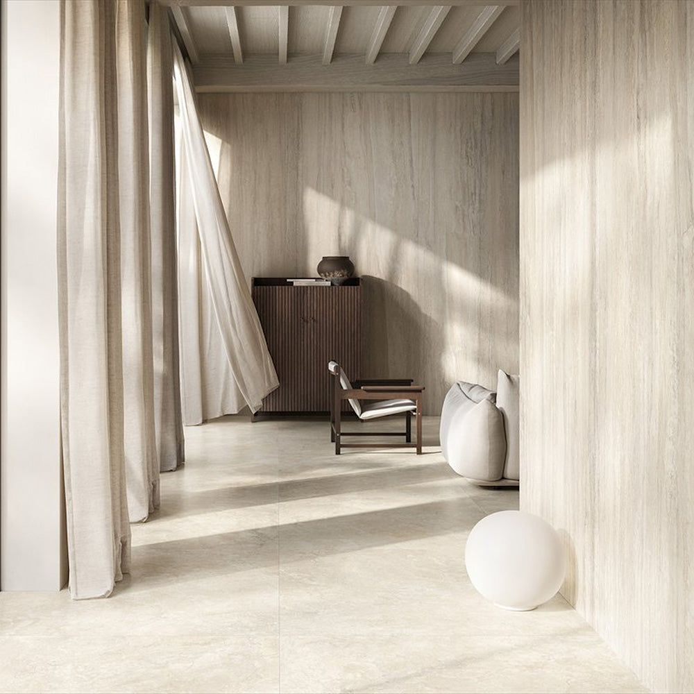 Living room featuring Nucetto Travertine 60x60cm wall and floor tiles, showcasing a soft travertine effect in warm cream and beige tones, extending seamlessly from the interior to the outdoor terrace for a calm, contemporary indoor-outdoor design.