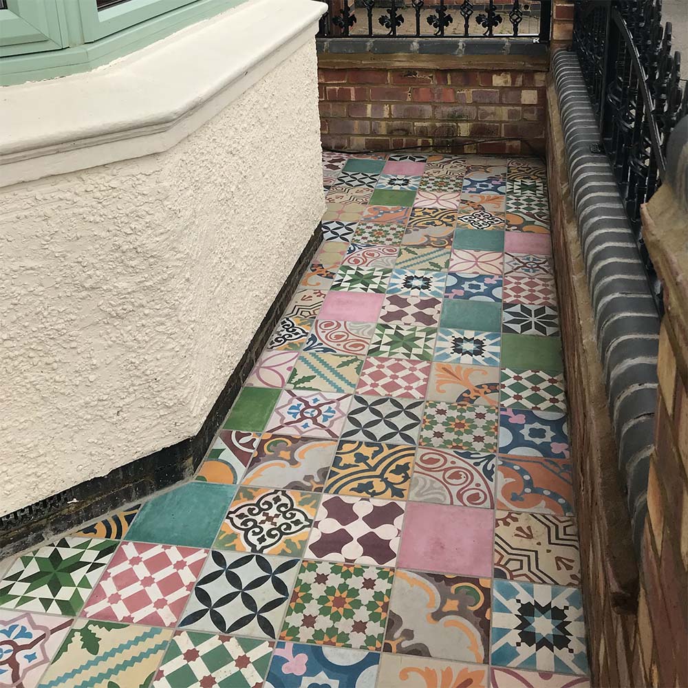 Outdoor entrance pathway featuring Fayrouz Patchwork 20×20cm Moroccan-style porcelain floor tiles, showcasing a vibrant mix of colourful geometric and floral designs arranged in a decorative patchwork layout.