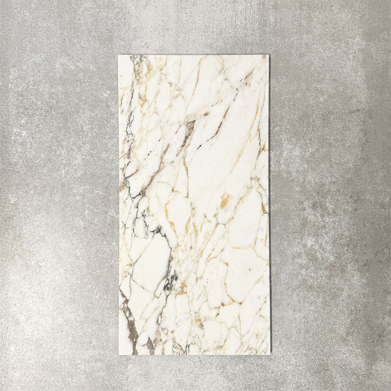 Fayrouz Picasso 30.5x61cm natural marble tiles with a honed finish, featuring a white base with intricate gold and grey veining, shown as a single tile sample against a neutral textured backdrop.