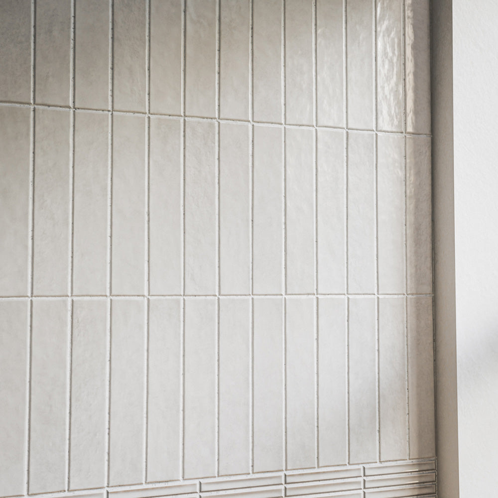 Close-up of Pottery Brick Blanco 5 × 25cm ceramic wall tiles, featuring soft white tones, subtle tonal variation, and a glossy handcrafted finish in a slim brick format for a refined contemporary wall design.