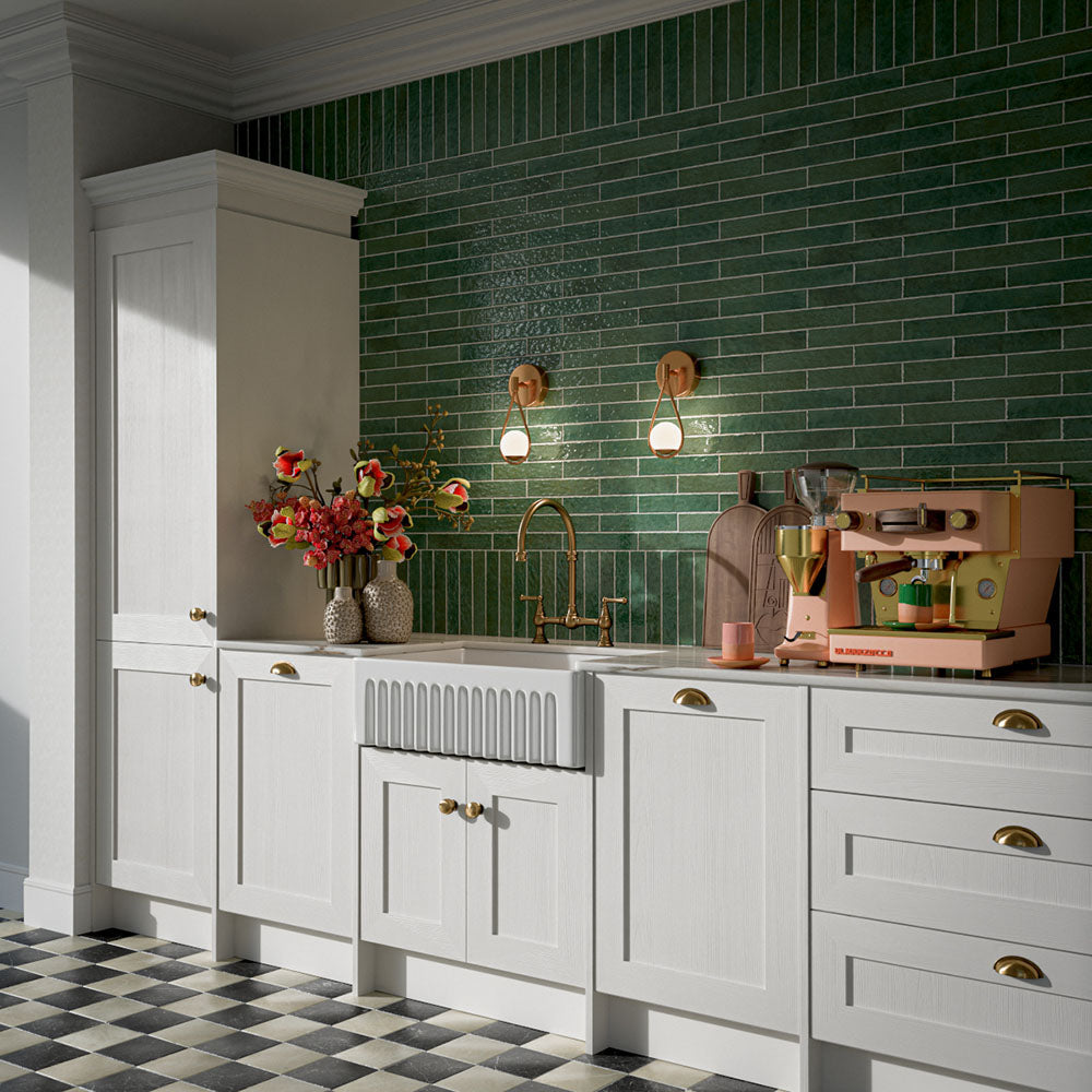 Kitchen featuring Pottery Forest Green 5x25cm glossy brick wall tiles, styled with cream shaker cabinetry, brass fixtures, a Belfast sink, and chequerboard floor tiles for a warm, vintage-inspired interior.