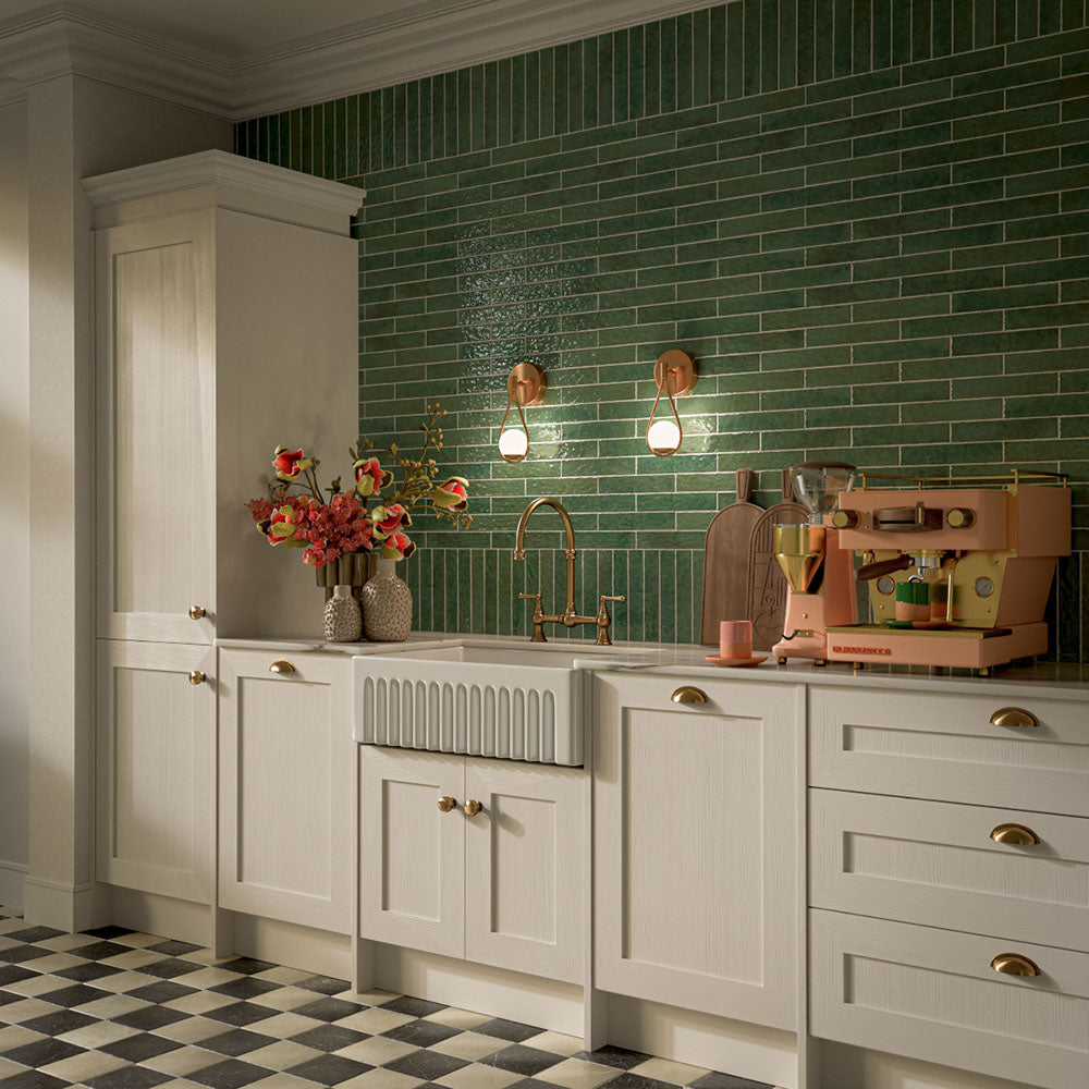 Kitchen featuring Pottery Forest Green 5x25cm glossy brick wall tiles, styled with cream shaker cabinetry, brass fixtures, a Belfast sink, and chequerboard floor tiles for a warm, vintage-inspired interior.