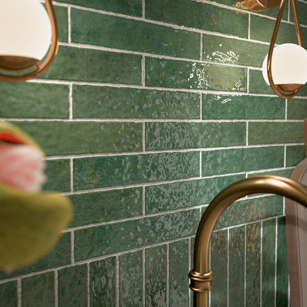Kitchen featuring Pottery Forest Green 5x25cm glossy brick wall tiles, styled with cream shaker cabinetry, brass fixtures, a Belfast sink, and chequerboard floor tiles for a warm, vintage-inspired interior.