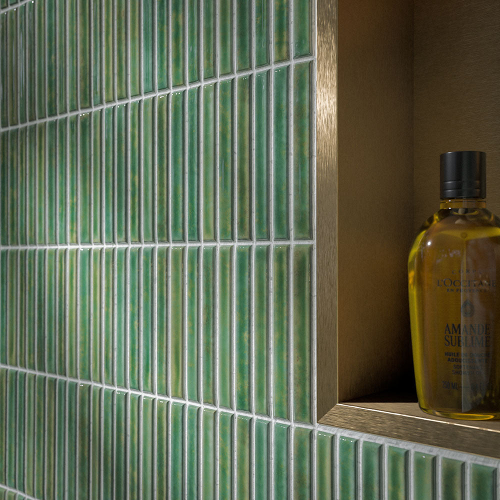 Walk-in shower featuring Pottery Decor Forest Green 12.5 × 25cm ceramic wall tiles, showcasing a rich glossy green finish with a vertically lined textured surface, paired with brass shower fittings and a recessed niche for a refined spa-inspired look.