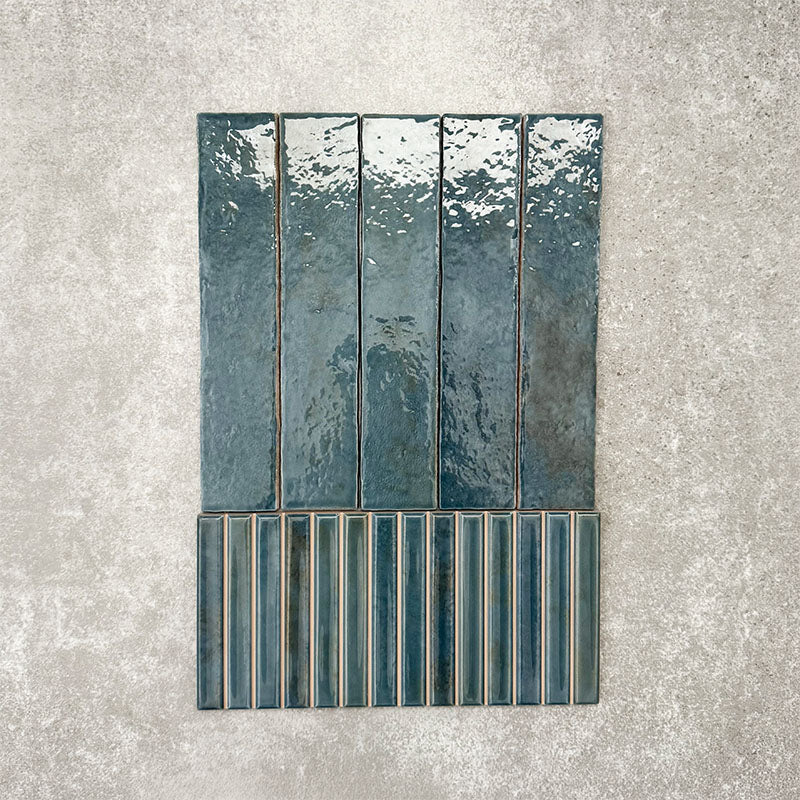 Product display of Pottery Decor Prussian 12.5x25cm ceramic wall tiles in deep blue tones, featuring a handcrafted glossy finish with coordinating fluted decorative tiles for textured contemporary interiors.