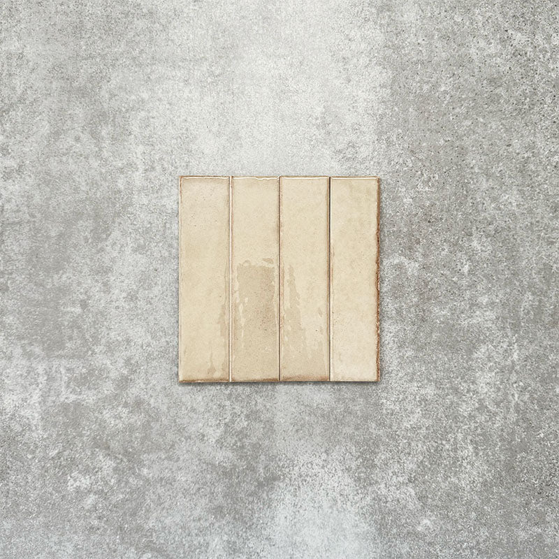 Product image of Puzzle Cream Brick Rectified 5x20cm wall and floor tiles, featuring a glossy cream finish with subtle shade variation and softly aged edges, displayed to highlight the tile's handcrafted character.