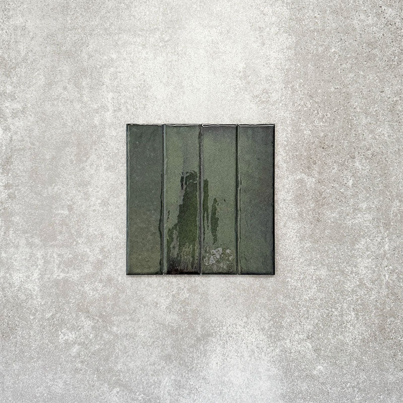 Product image of Puzzle Forest Green Brick Rectified 5x20cm wall and floor tiles, featuring a glossy deep green finish with rich tonal variation and softly aged edges, displayed to highlight the tile's handcrafted character.
