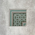 Single London Streets Regent Street Corner 20x20cm Victorian Moroccan style porcelain tile displayed in a product setting, featuring a decorative border corner design in green, sage and cream tones inspired by traditional Victorian entrance hall tile layouts.