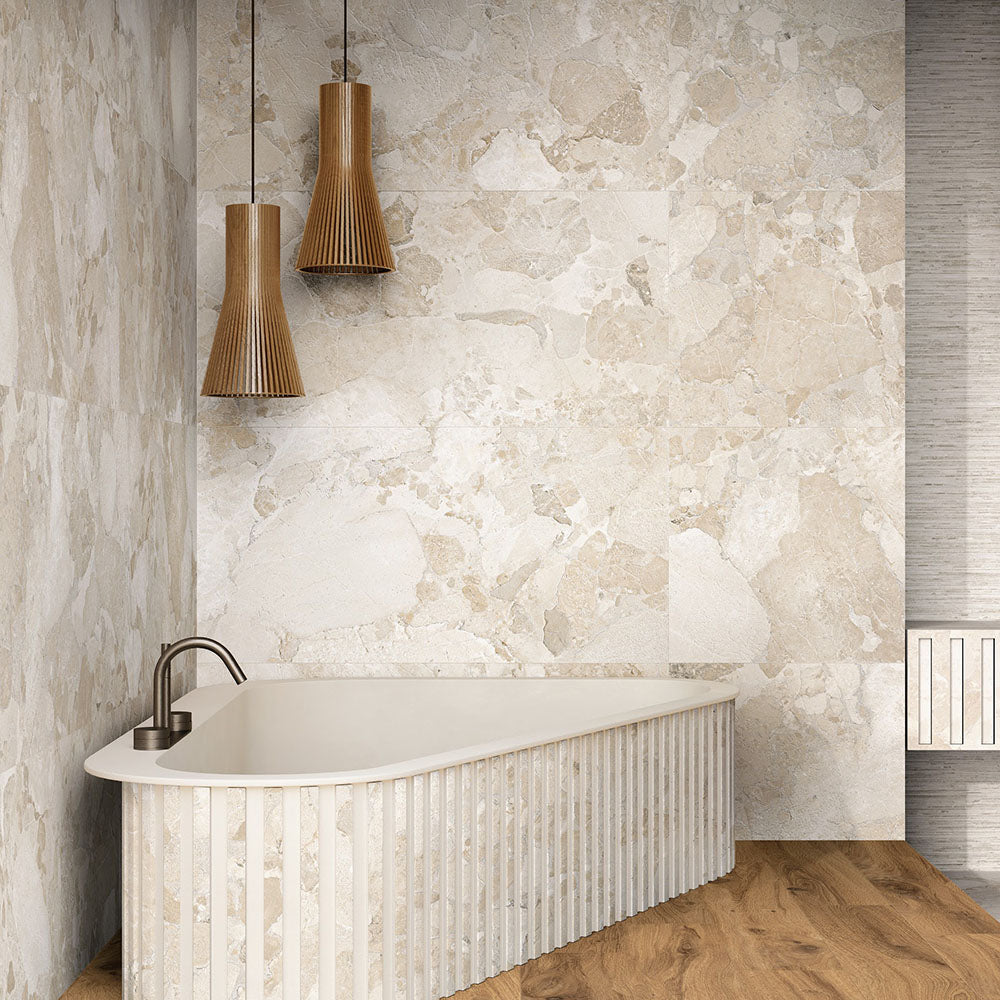 Bathroom featuring Riad Avorio Sassi Stone 30x60cm stone-effect wall and floor tiles, showcasing warm ivory and beige tones with natural stone-inspired detailing, paired with a freestanding fluted bath, timber flooring and wooden pendant lights.