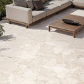Contemporary outdoor patio featuring Riad Avorio Terrazzo 20mm 100x100cm outdoor stone-effect porcelain tile slabs, showcasing warm ivory and beige tones, paired with minimalist lounge seating, timber furniture and landscaped gardens.