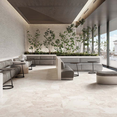 Contemporary lounge featuring Riad Blanco Sassi Terrazzo Stone 60x120cm stone-effect floor tiles, showcasing soft cream and beige tones with natural stone-inspired detailing, paired with minimalist seating, indoor planting and floor-to-ceiling glazing.
