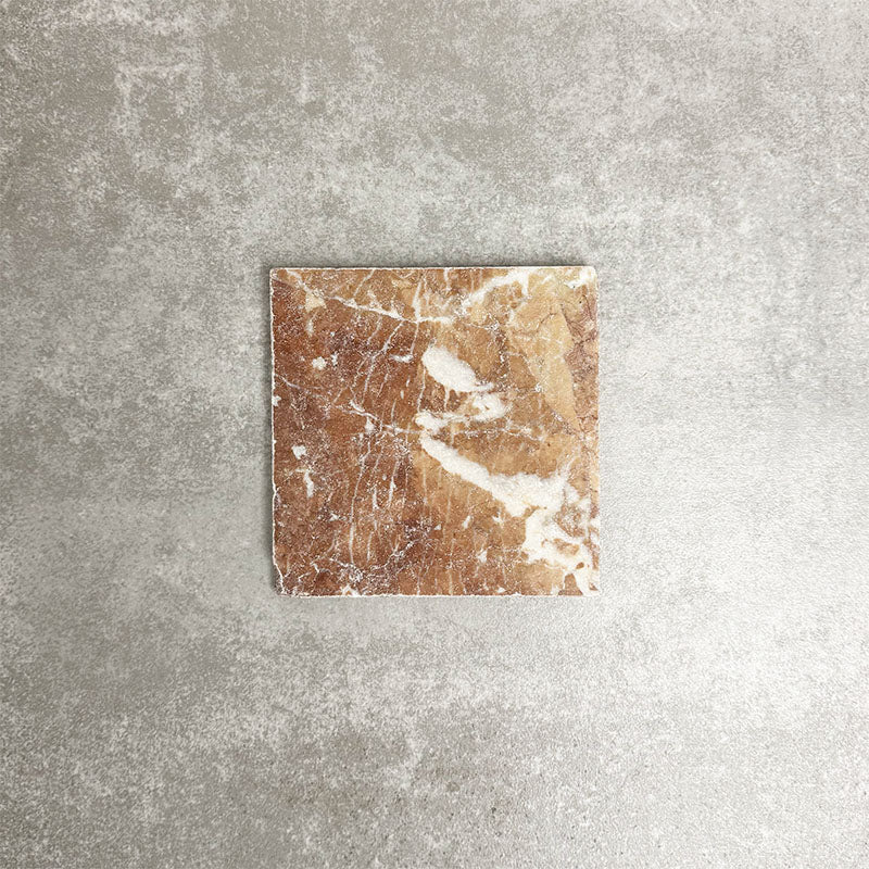 Single Fayrouz Rosso 15.2x15.2cm natural marble tile with a tumbled finish, featuring warm red tones and striking natural veining, displayed against a neutral textured background in a clean product setting.