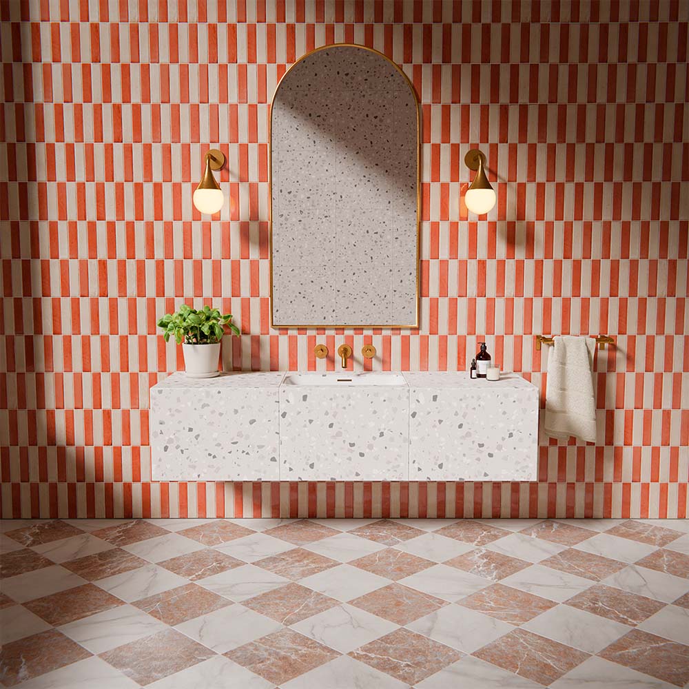 Puzzle Coral Brick Rectified 5x20cm wall and floor tiles in a vertical stacked layout, featuring warm coral and white tones in a contemporary bathroom setting with terrazzo vanity and brass fixtures.