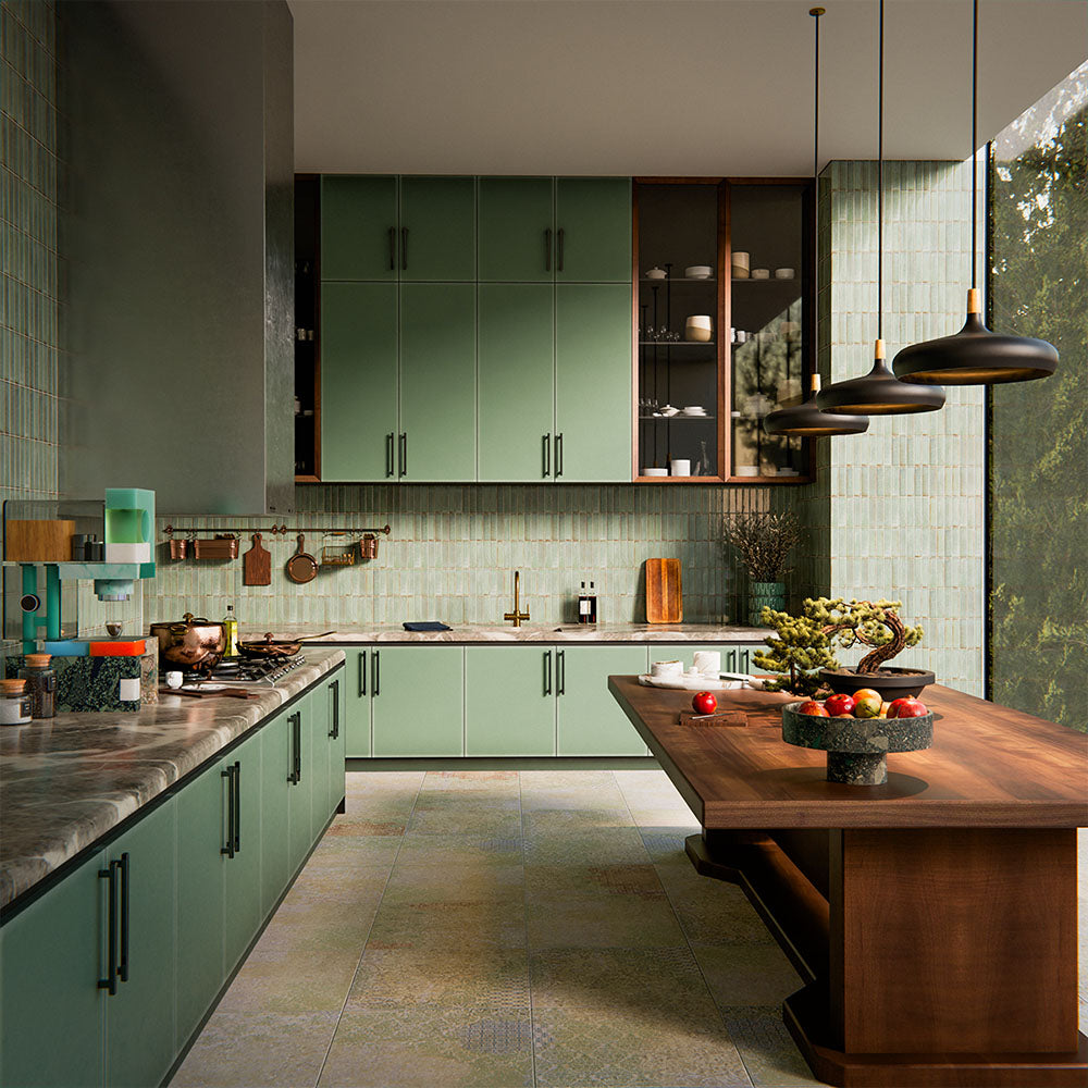 Puzzle Sage Green Brick Rectified 5x20cm porcelain tiles used as a full-height kitchen splashback, showcasing soft sage green tones with subtle speckling and natural shade variation. The slim brick format enhances vertical lines and texture, pairing beautifully with matching cabinetry, warm wood finishes and brass accents for a cohesive, contemporary kitchen design.