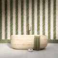Bathroom interior featuring Nomad Sage Green and Nomad Oatmeal 6 x 24.6cm industrial style brick tiles, arranged in a striking herringbone pattern to create a layered, textural wall design, paired with a natural stone bath and soft neutral flooring for a calm, contemporary finish.