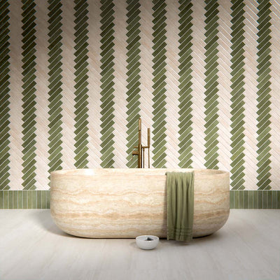 Bathroom interior featuring Nomad Sage Green and Nomad Oatmeal 6 x 24.6cm industrial style brick tiles, arranged in a striking herringbone pattern to create a layered, textural wall design, paired with a natural stone bath and soft neutral flooring for a calm, contemporary finish.