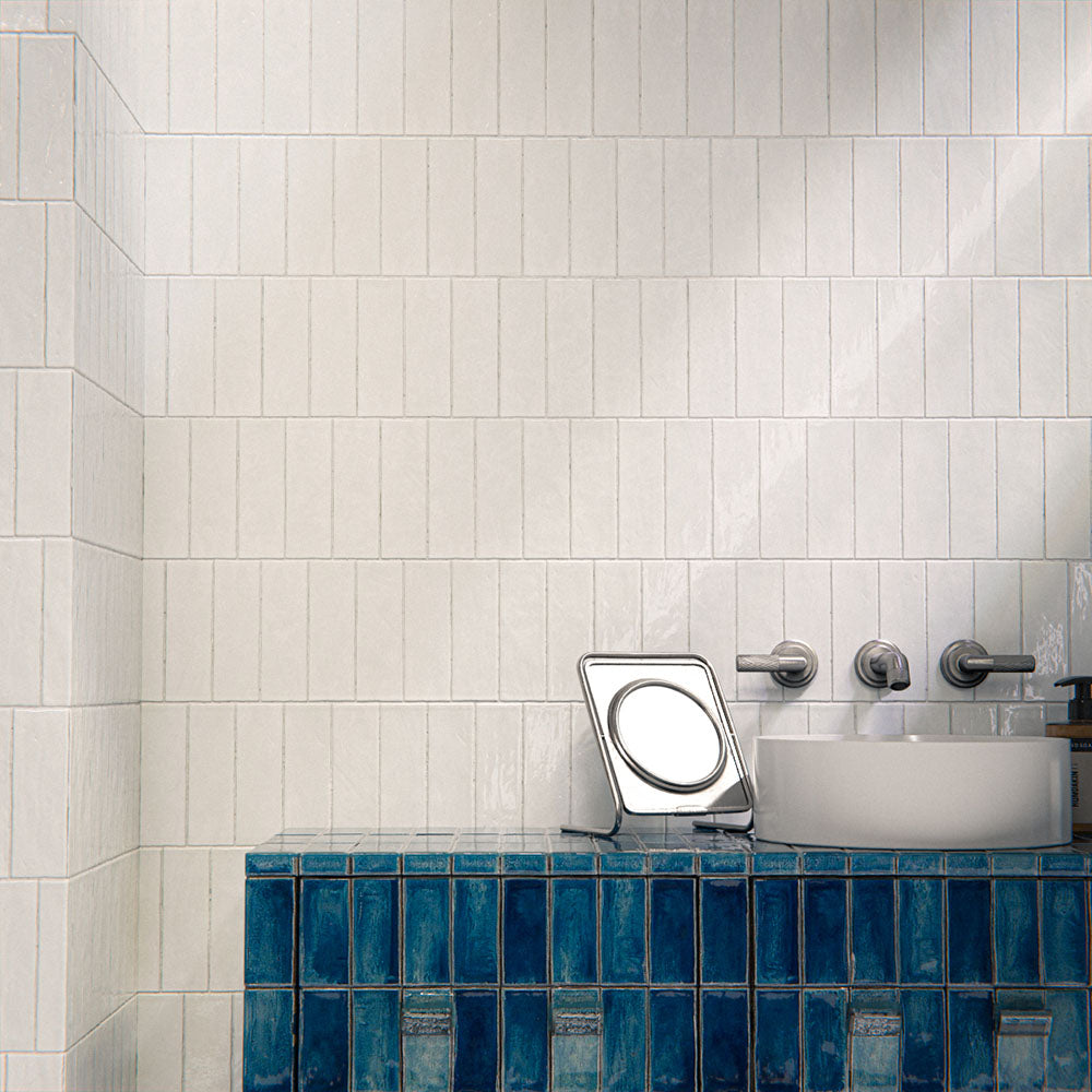 Bathroom interior featuring Foundry Bricks Arctic White 6.5x20cm ceramic wall tiles in a horizontal layout, styled with a blue tiled vanity, countertop basin and brushed metal fixtures.