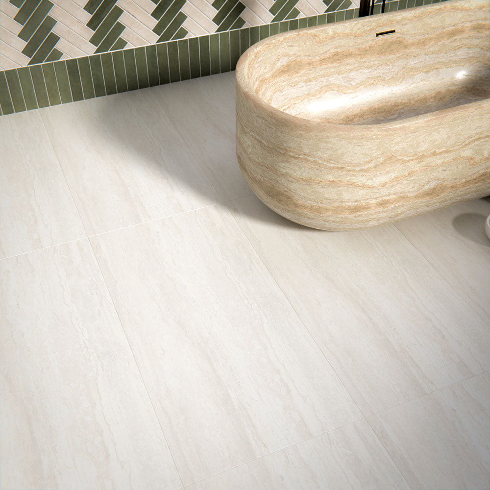 Bathroom interior featuring Trevi Stone 60 x 120cm porcelain floor tiles in a soft matt finish, showcasing a subtle natural stone effect in warm neutral tones, paired with a statement freestanding bath and patterned wall tiles to create a calm, balanced space.
