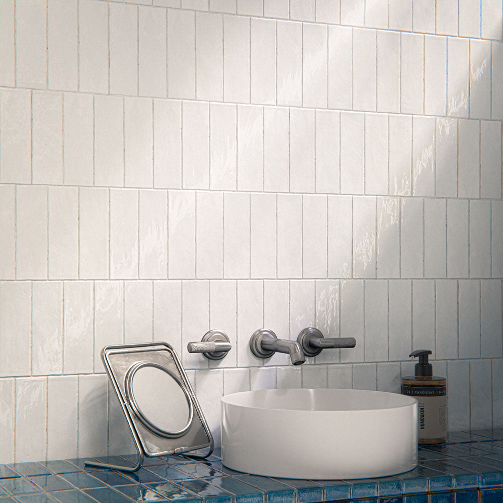 Bathroom interior featuring Foundry Bricks Arctic White 6.5x20cm ceramic wall tiles in a horizontal layout, styled with a blue tiled vanity, countertop basin and brushed metal fixtures.