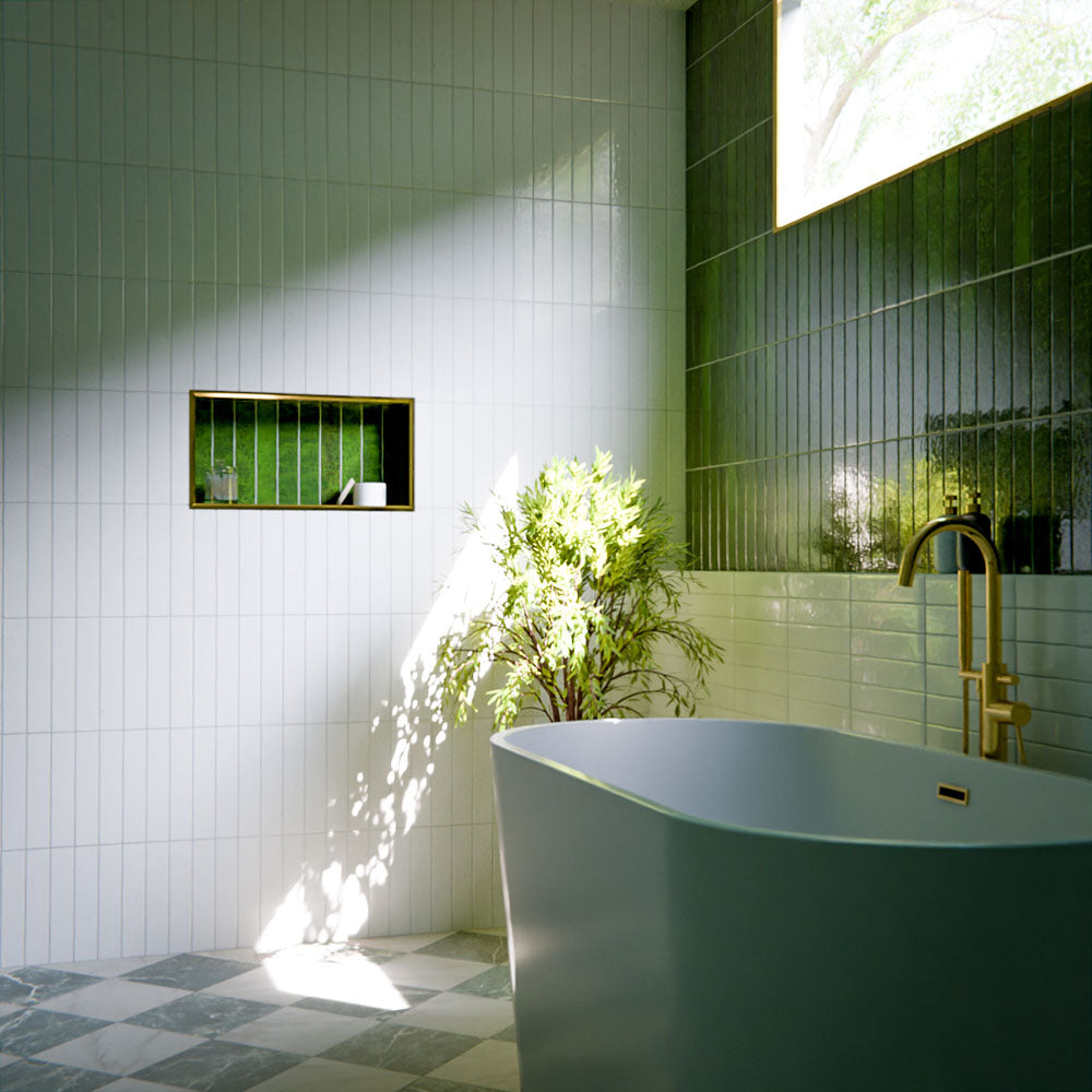 Modern bathroom featuring Bora Bora White Sand Brick ceramic wall tiles in a 6.5 × 32.8cm slim brick format with a flux glaze finish, laid vertically and horizontally to create a soft, textured feature wall, paired with a freestanding bath, brass tapware, natural light, and greenery for a calm, spa-like atmosphere.