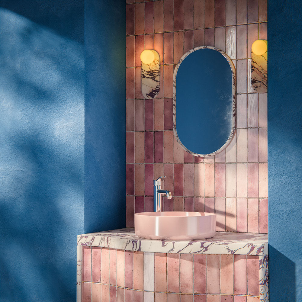 Bathroom interior featuring Foundry Bricks Coral Pink 6.5x20cm ceramic wall tiles in a vertical layout, styled with a curved vanity, blush basin, marble-effect worktop and brushed brass lighting.