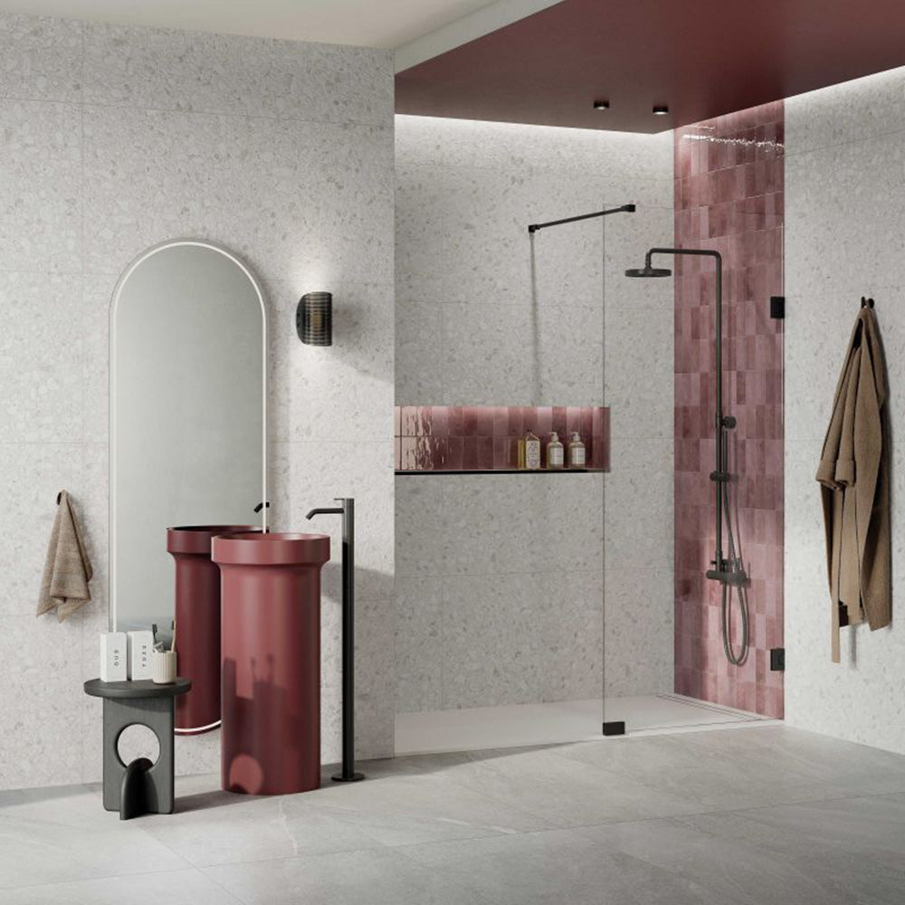 Contemporary bathroom featuring Shards Blanco 3D Terrazzo 60x120cm porcelain wall tiles, showcasing a white terrazzo effect with textured 3D stone chips, paired with a burgundy feature basin, pink gloss shower tiles, black fittings and a frameless walk-in shower.