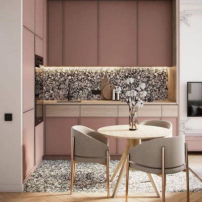 Kitchen featuring Shards Terrazzo Nero Matt 59x118cm porcelain wall and floor tiles in black and white terrazzo-effect tones, styled with blush pink cabinetry, light wood finishes, and contemporary dining furniture.