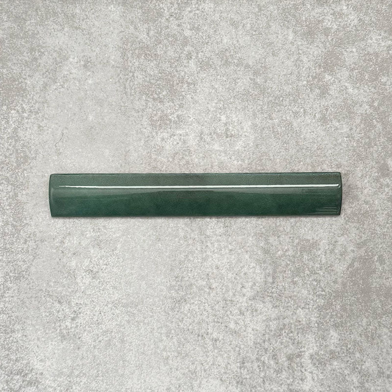 Zellige Royal Green Bullnose 3 × 20cm Moroccan-style ceramic trim tile in rich deep green tones, displayed with a smooth rounded edge and glossy glaze, arranged on a textured grey background to highlight the handcrafted zellige-effect finish and decorative edging profile.