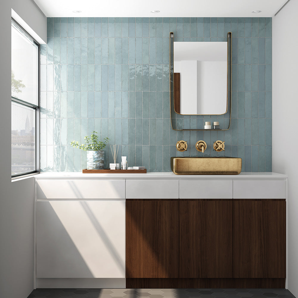 Nomad Aquamarine brick wall tiles in a 6 × 24.6cm format with a glossy, lightly textured finish, installed vertically in a bathroom vanity setting with brass fittings for a clean industrial look.