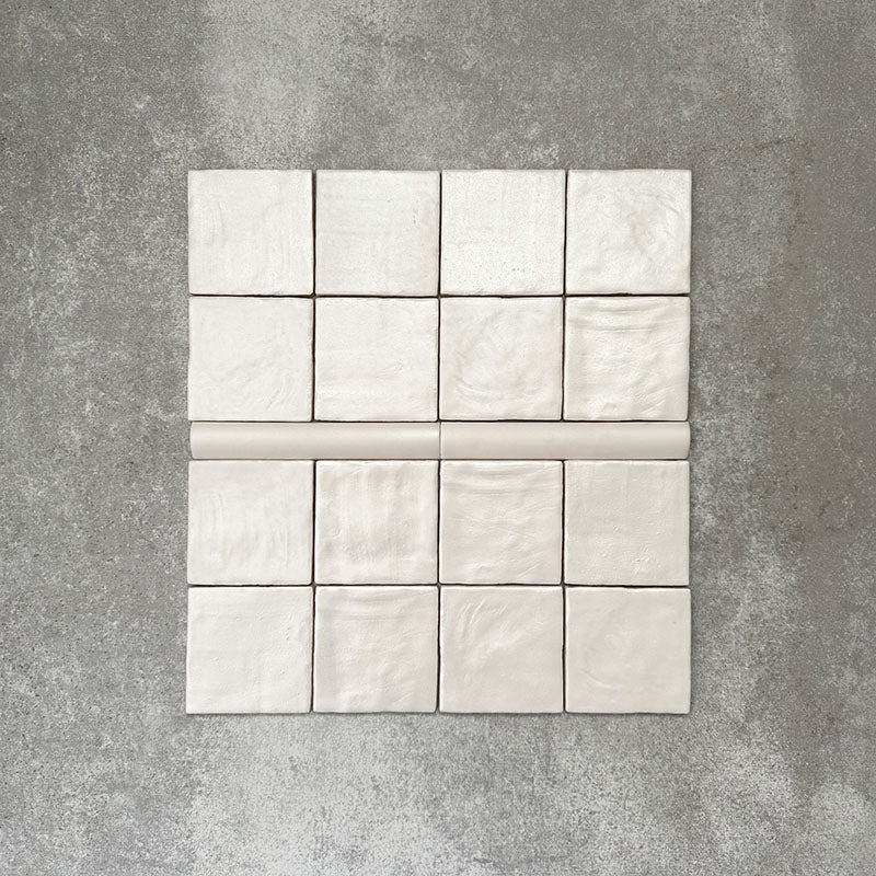 Zellige Oyster square tiles with matching bullnose trim in an oyster white finish, laid flat to show texture and shape.