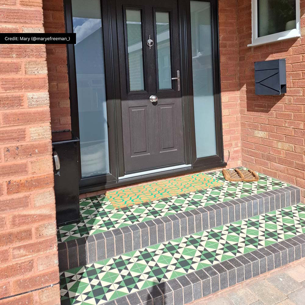 Front doorstep featuring Greenbrook Manor anti-slip encaustic Victorian-style porcelain tiles, laid on exterior steps in a bold green, black and white geometric pattern, complementing a black front door and brick façade.