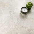 Kitchen surface featuring Essentials Terrazzo Stone Blanca 60x120cm terrazzo effect porcelain tiles, styled with a ceramic candle and green glass vessel, highlighting soft white and beige stone-inspired variation.