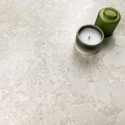 Kitchen surface featuring Essentials Terrazzo Stone Blanca 60x120cm terrazzo effect porcelain tiles, styled with a ceramic candle and green glass vessel, highlighting soft white and beige stone-inspired variation.