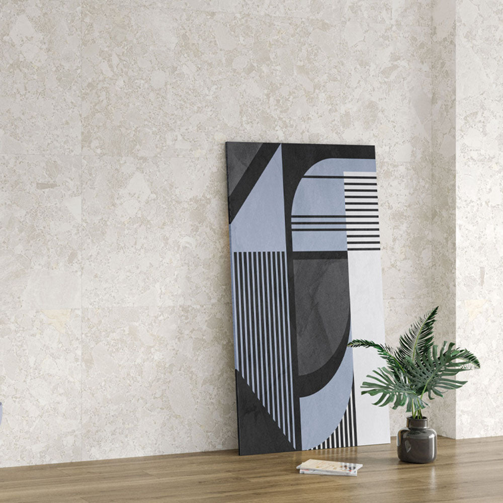 Interior wall featuring Essentials Terrazzo Stone Blanca 60x120cm terrazzo effect porcelain tiles, styled with abstract artwork, a wooden surface, and a small plant to highlight the soft stone-inspired pattern and tonal variation.