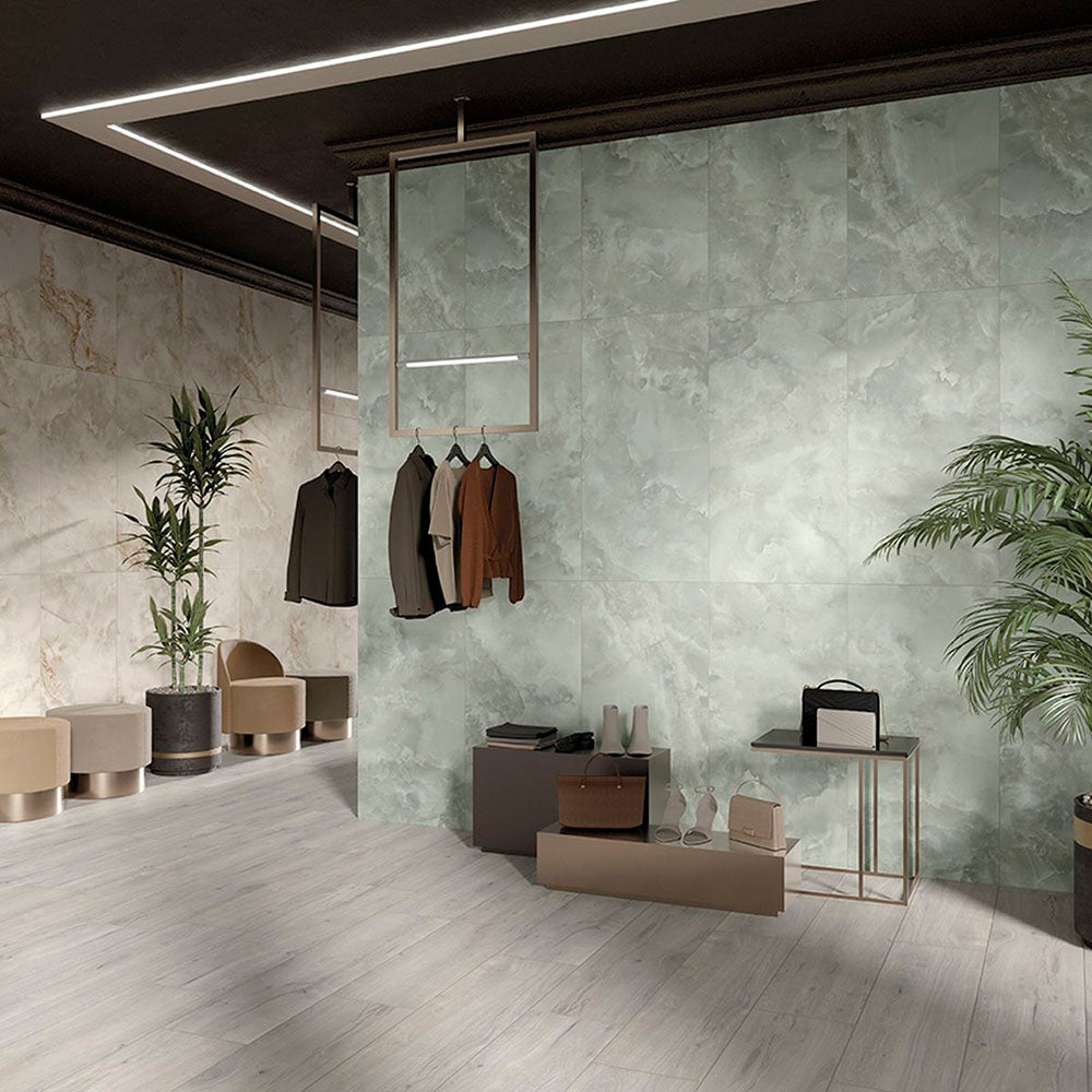 Contemporary commercial interior featuring Thebes Ivory Honed Matt Onyx porcelain tiles as a large-format feature wall. The soft ivory onyx-effect veining creates a refined focal point, complemented by pale wood effect flooring, indoor greenery and minimalist furnishings for a bright, luxurious space.