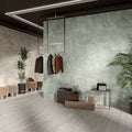 Contemporary commercial interior featuring Thebes Ivory Honed Matt Onyx porcelain tiles as a large-format feature wall. The soft ivory onyx-effect veining creates a refined focal point, complemented by pale wood effect flooring, indoor greenery and minimalist furnishings for a bright, luxurious space.