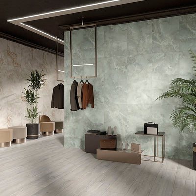 Contemporary commercial interior featuring Thebes Ivory Honed Matt Onyx porcelain tiles as a large-format feature wall. The soft ivory onyx-effect veining creates a refined focal point, complemented by pale wood effect flooring, indoor greenery and minimalist furnishings for a bright, luxurious space.