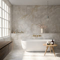 Luxury bathroom featuring Thebes White honed matt onyx effect porcelain wall and floor tiles in a large-format 60cm x 120cm design, paired with a freestanding bath, brushed brass fittings, floating wood vanity, soft natural light and contemporary spa-inspired styling.