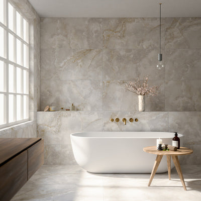 Luxury bathroom featuring Thebes White honed matt onyx effect porcelain wall and floor tiles in a large-format 60cm x 120cm design, paired with a freestanding bath, brushed brass fittings, floating wood vanity, soft natural light and contemporary spa-inspired styling.