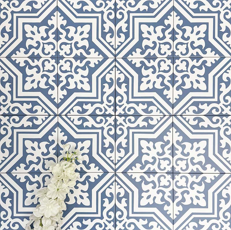 Overhead view of London Streets Thornton Place 20x20cm Victorian Moroccan style porcelain tiles arranged in a repeating blue and white patterned layout, styled with decorative foliage to highlight the intricate traditional Victorian-inspired floor design.