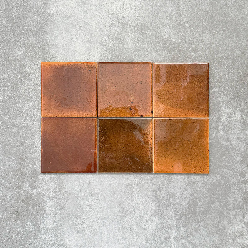 Close-up of Saigon Amber Square Wall tiles in a Moroccan-inspired style, 10 × 10cm glossy ceramic tiles with warm amber and copper colour variations.