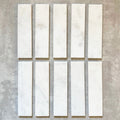 Fayrouz White 5x20cm natural marble tiles with a honed finish, featuring a soft white base with subtle grey veining, arranged in a neat grid to highlight natural variation and tonal consistency.