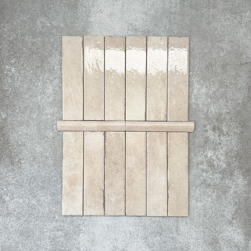 Nomad Oatmeal bullnose pencil border ceramic tiles in a 3 × 20cm format, shown with matching brick tiles to highlight the warm oatmeal tone, gloss finish and rounded edge detail.