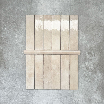 Nomad Oatmeal bullnose pencil border ceramic tiles in a 3 × 20cm format, shown with matching brick tiles to highlight the warm oatmeal tone, gloss finish and rounded edge detail.